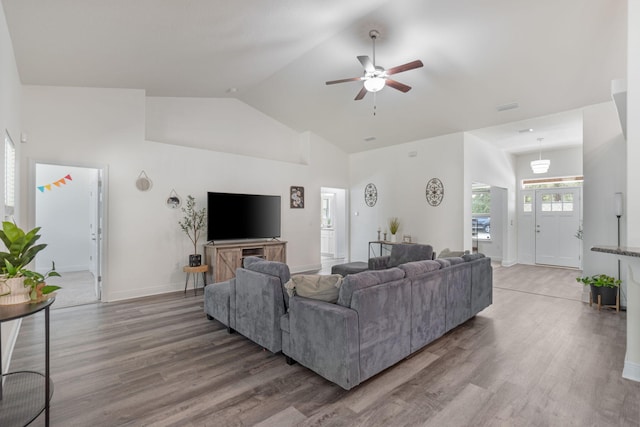 living area with baseboards, high vaulted ceiling, light wood-style flooring, and a ceiling fan