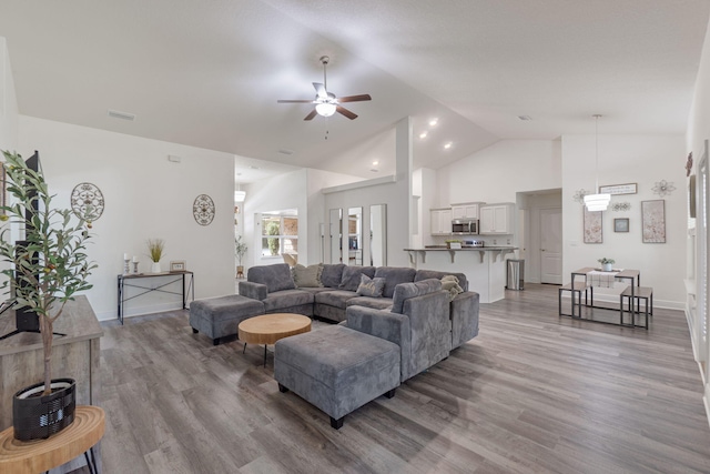 living area featuring high vaulted ceiling, light wood-type flooring, visible vents, and ceiling fan