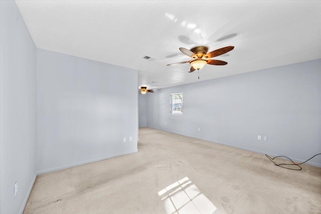 carpeted empty room featuring baseboards, visible vents, and a ceiling fan