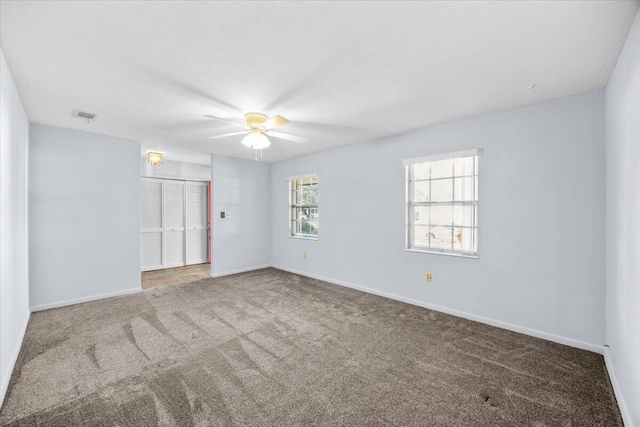 carpeted spare room featuring baseboards, visible vents, and a ceiling fan