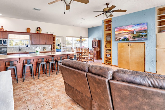 617 E E Gorrie Dr, Saint George Island, FL 32328 - living room with visible vents, built in features, ceiling fan with notable chandelier, a textured wall, and light tile patterned floors