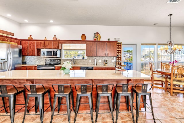 617 E E Gorrie Dr, Saint George Island, FL 32328 - kitchen with backsplash, light tile patterned floors, a kitchen breakfast bar, and stainless steel appliances