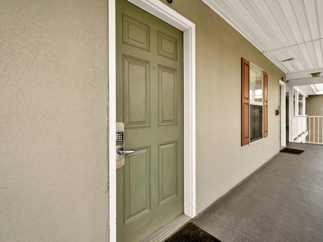 doorway to property with covered porch and stucco siding