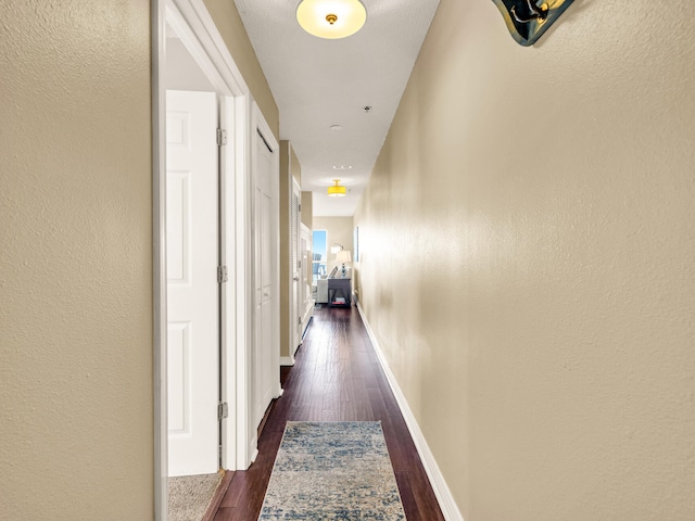 hallway with dark wood-style flooring and baseboards