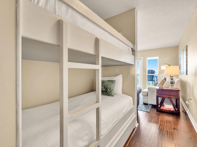 bedroom with baseboards, hardwood / wood-style flooring, and a textured ceiling