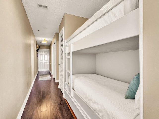bedroom featuring a textured ceiling, wood finished floors, baseboards, and visible vents