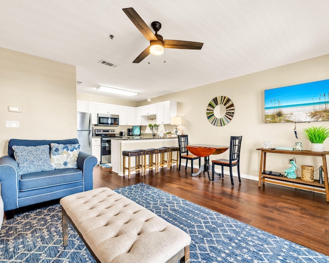 living area with visible vents, ceiling fan, wood finished floors, and baseboards