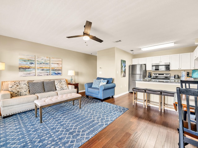 living room featuring dark wood-type flooring, visible vents, ceiling fan, and baseboards