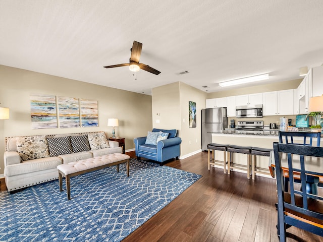 living room featuring dark wood-type flooring, baseboards, a ceiling fan, and visible vents