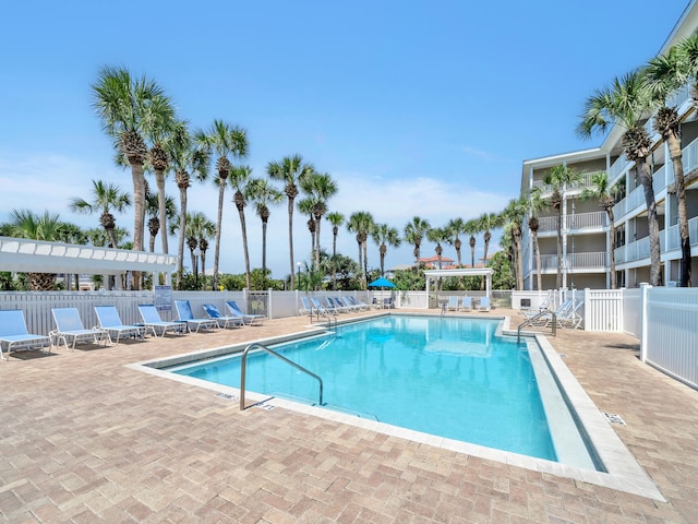 community pool with a pergola, a patio, and fence