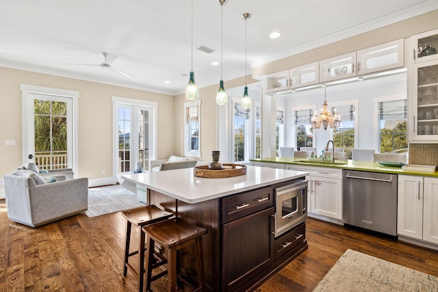 kitchen featuring crown molding, a kitchen bar, open floor plan, stainless steel appliances, and visible vents