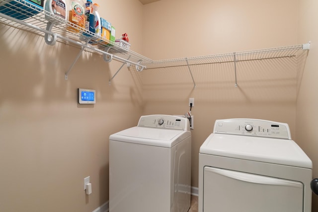 laundry room featuring washing machine and clothes dryer, baseboards, and laundry area