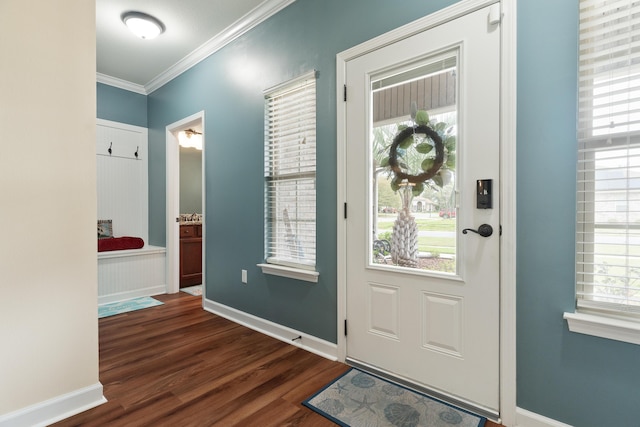 foyer with dark wood-style flooring, crown molding, and baseboards