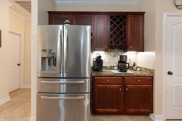 kitchen featuring dark stone countertops, ornamental molding, light tile patterned floors, baseboards, and stainless steel refrigerator with ice dispenser