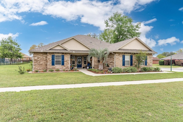view of front of house with brick siding, roof with shingles, a front yard, and fence