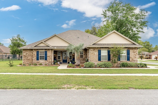 craftsman house featuring fence, a front lawn, brick siding, and roof with shingles