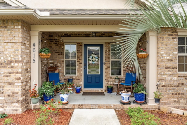 property entrance with a porch and brick siding