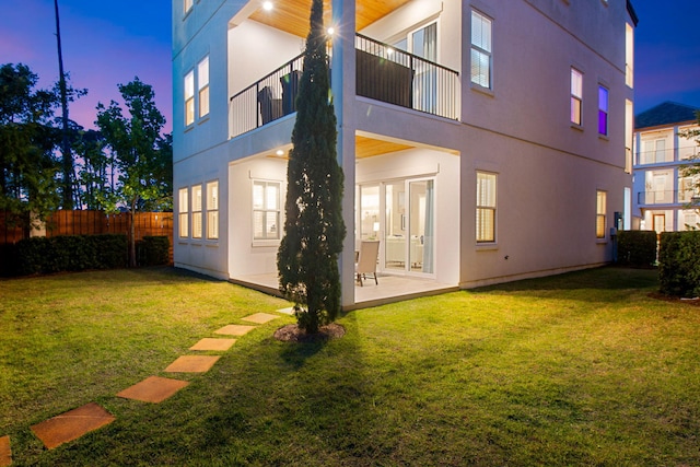 43 Calla Way, Miramar Beach, FL 32550 - back of property at dusk with fence, a patio, stucco siding, and a lawn