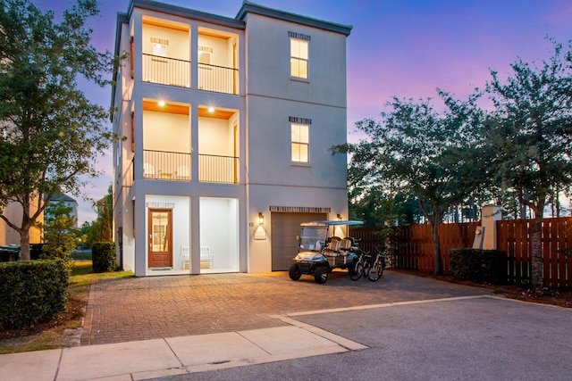 43 Calla Way, Miramar Beach, FL 32550 - rear view of house with fence, an attached garage, aphalt driveway, stucco siding, and a balcony