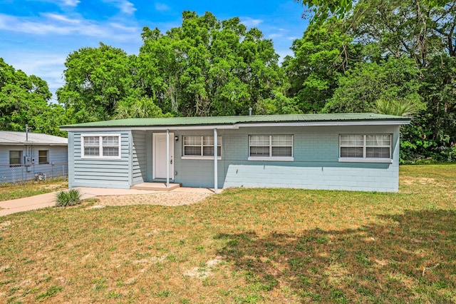 ranch-style home featuring concrete block siding and metal roof