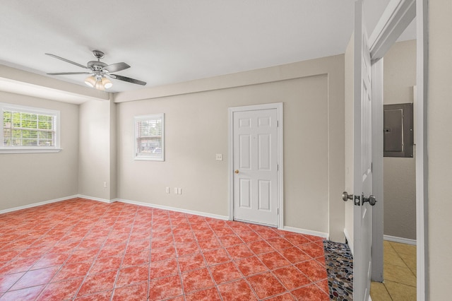spare room featuring electric panel, ceiling fan, light tile patterned flooring, and baseboards