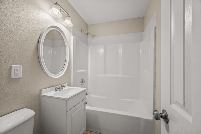 full bathroom with vanity, toilet,  shower combination, and a textured wall