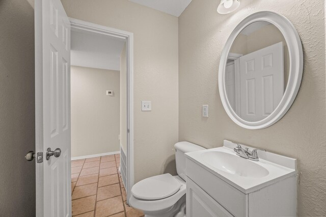 half bathroom featuring toilet, vanity, and tile patterned floors