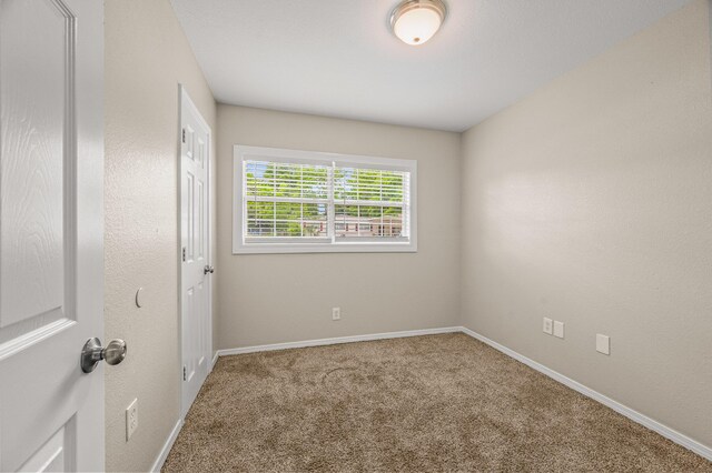 carpeted spare room featuring baseboards