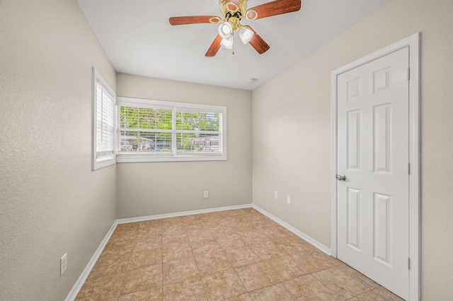 empty room featuring a ceiling fan and baseboards