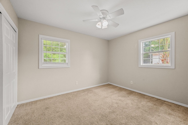 carpeted empty room with baseboards and a ceiling fan