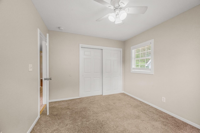 unfurnished bedroom featuring carpet, baseboards, a closet, and a ceiling fan