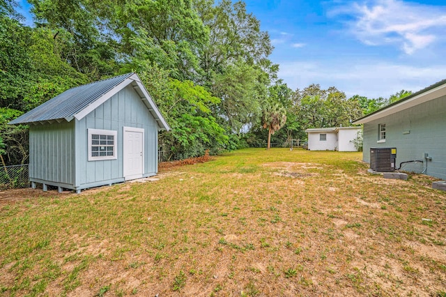 view of yard with central air condition unit, a storage unit, an outdoor structure, and view of wooded area