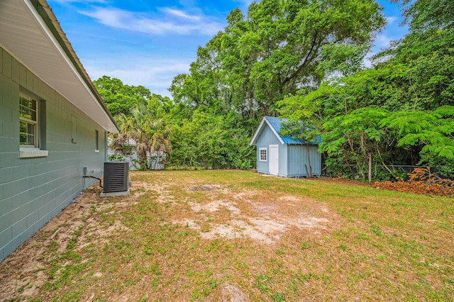 view of yard with a shed, central AC, an outbuilding, and view of scattered trees