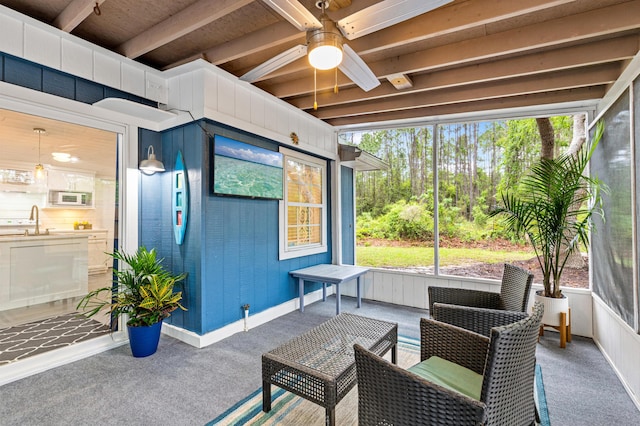 sunroom / solarium with ceiling fan, beam ceiling, and a sink