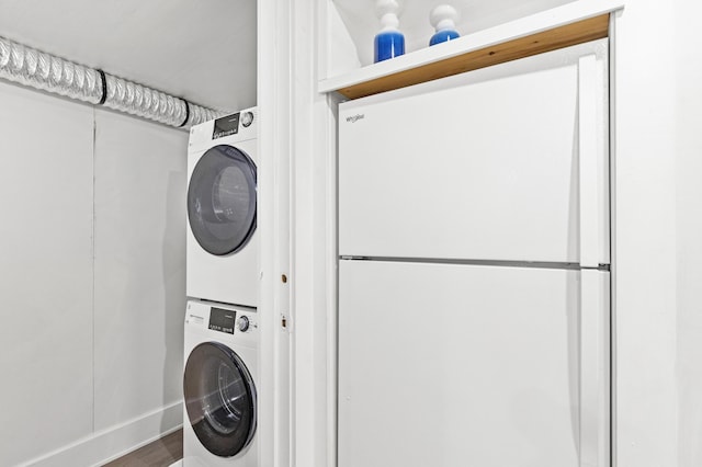 washroom with wood finished floors, stacked washer / dryer, and laundry area