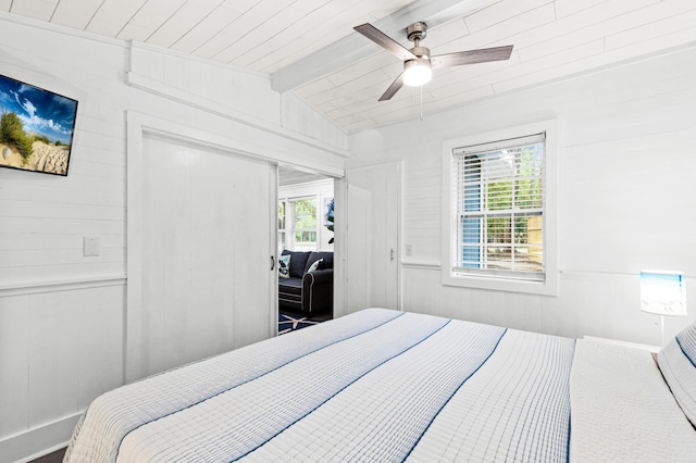 bedroom featuring vaulted ceiling with beams, a ceiling fan, wood walls, a closet, and wood ceiling
