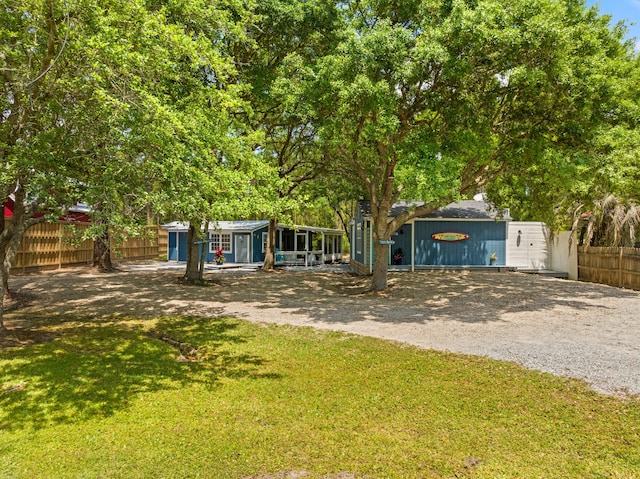 obstructed view of property featuring gravel driveway, fence, and a front yard