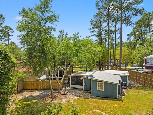 back of property with fence private yard, a sunroom, a yard, and metal roof