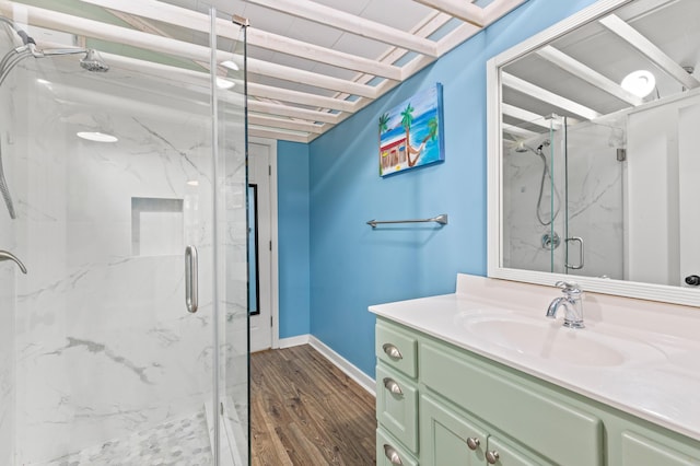 bathroom with baseboards, wood finished floors, a marble finish shower, and vanity