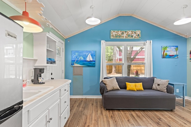 kitchen featuring refrigerator, light wood finished floors, baseboards, lofted ceiling, and white cabinetry