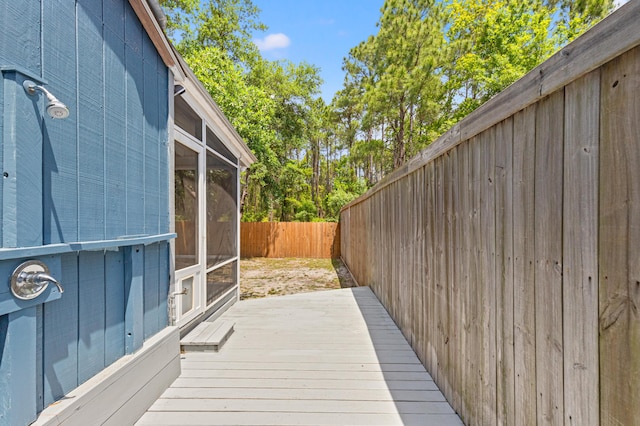 wooden deck featuring a fenced backyard and a sunroom