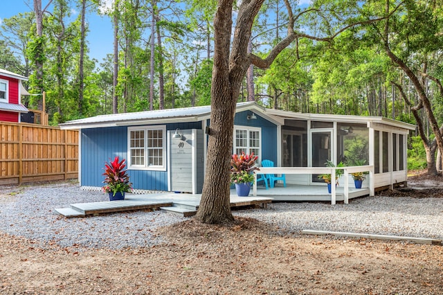 exterior space featuring fence, a deck, metal roof, and a sunroom