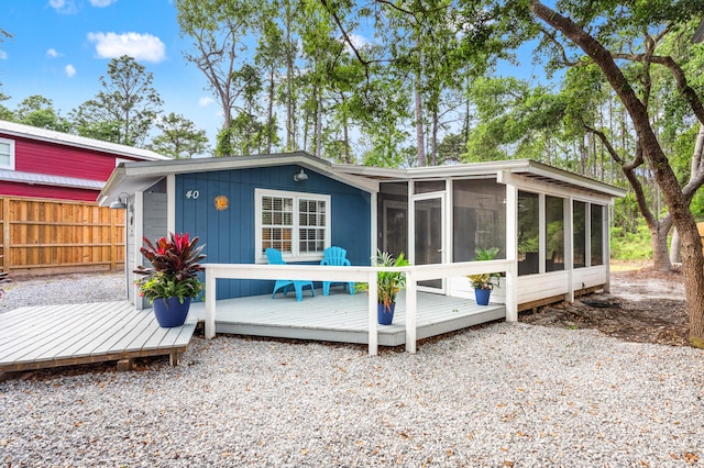 rear view of house featuring a deck, fence, and a sunroom