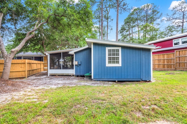 back of property with a fenced backyard, a yard, and a sunroom
