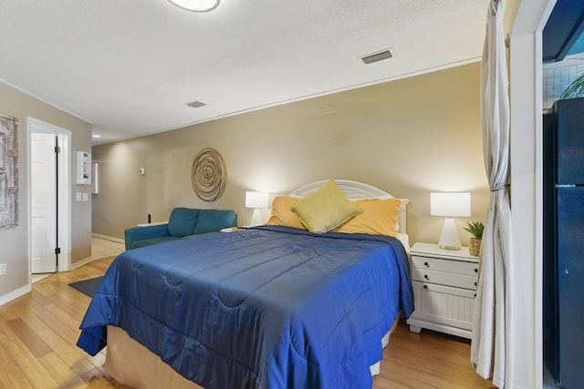 8730 Thomas Dr # 1210, Panama City Beach, FL 32408 - bedroom with light wood-style flooring, a textured ceiling, baseboards, and visible vents