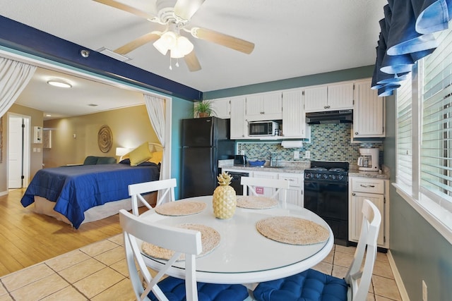 8730 Thomas Dr # 1210, Panama City Beach, FL 32408 - interior space with black appliances, under cabinet range hood, light tile patterned flooring, light countertops, and decorative backsplash