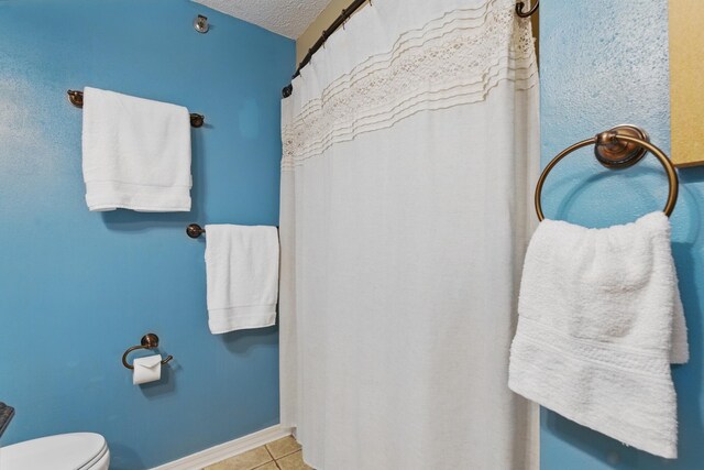 8730 Thomas Dr # 1210, Panama City Beach, FL 32408 - bathroom featuring toilet, tile patterned floors, baseboards, and a textured ceiling