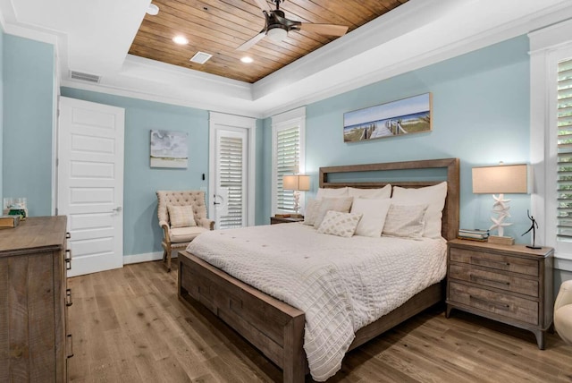 bedroom with wood ceiling, a tray ceiling, wood finished floors, baseboards, and a ceiling fan