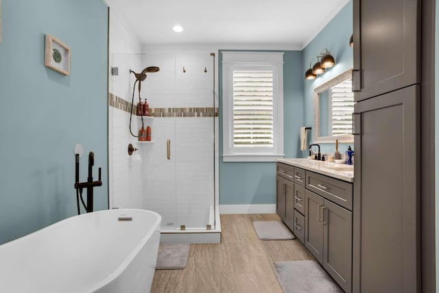 full bathroom featuring a stall shower, vanity, a freestanding tub, and baseboards