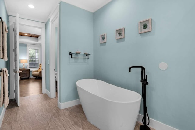 ensuite bathroom featuring a soaking tub, baseboards, and recessed lighting